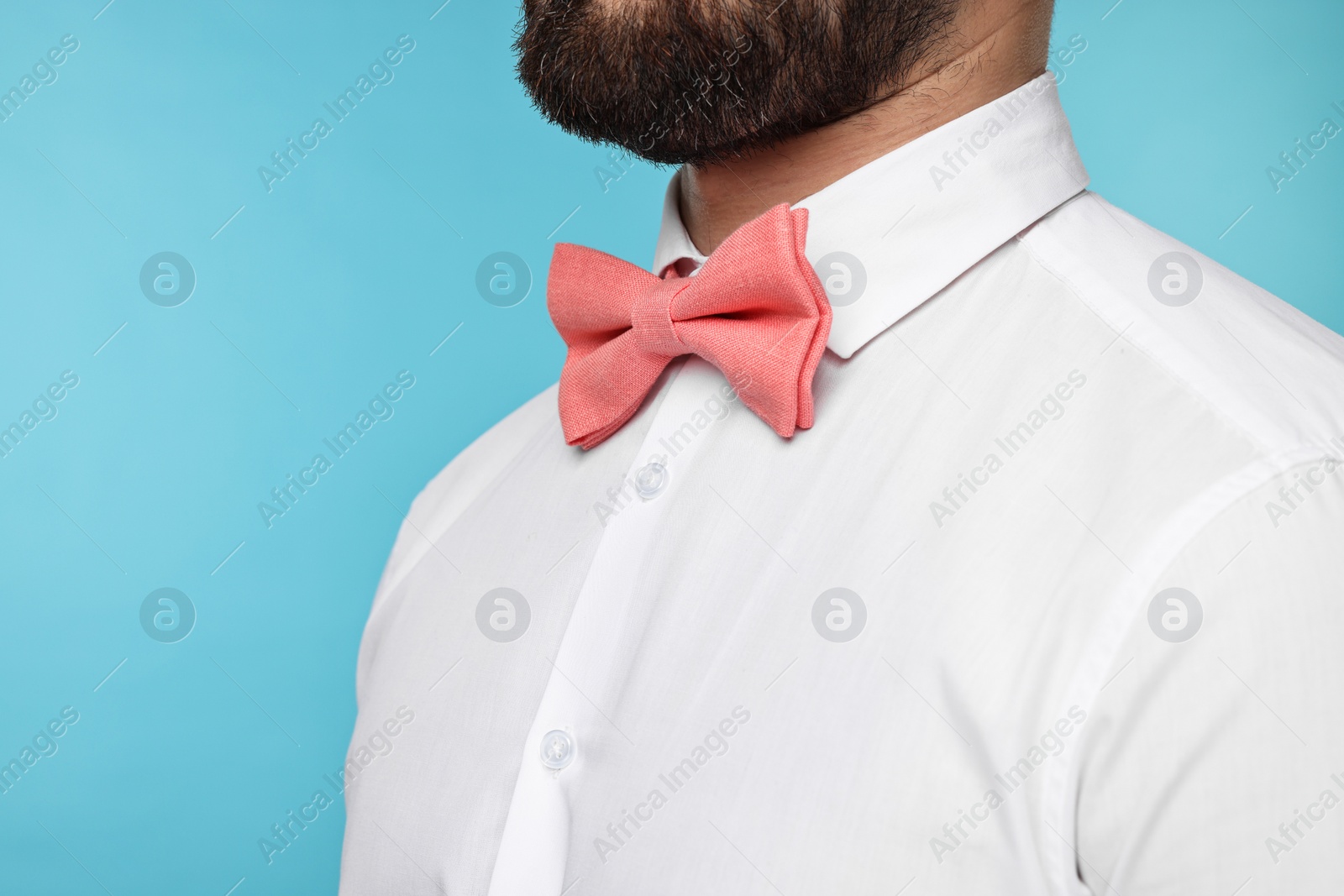 Photo of Man in shirt and bow tie on light blue background, closeup