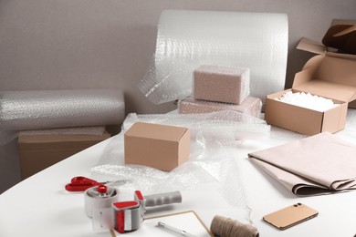 Photo of Table with boxes, bubble wrap and packaging equipment in warehouse