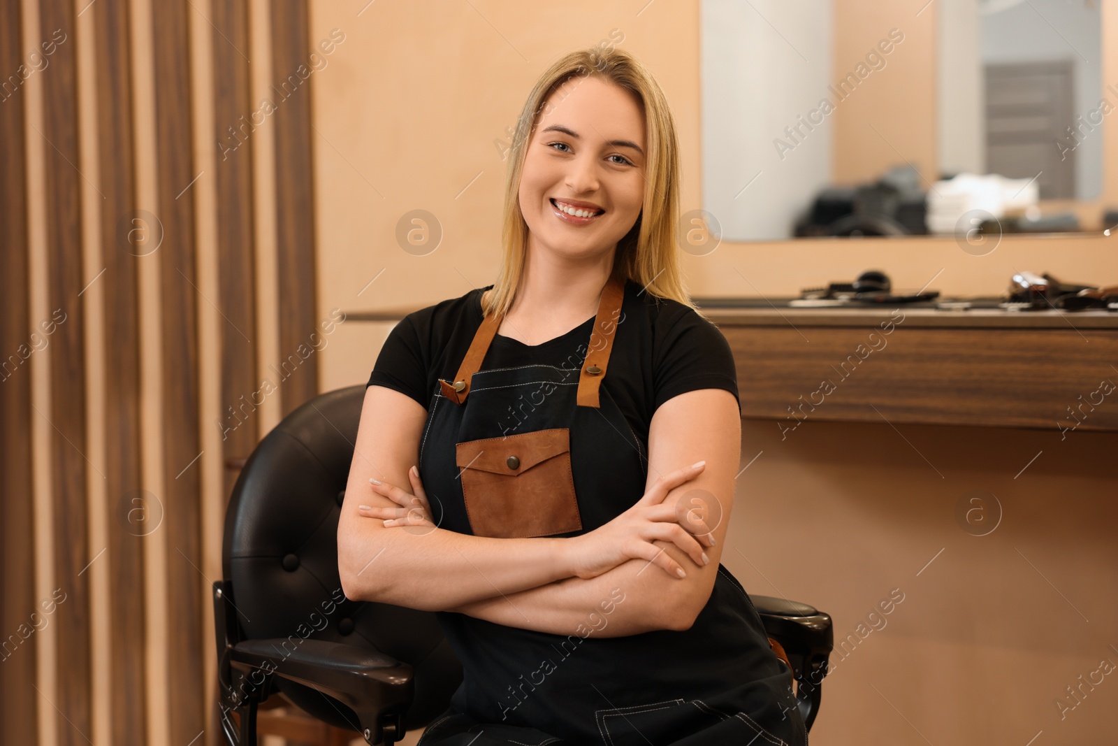 Photo of Portrait of professional hairdresser wearing apron in beauty salon