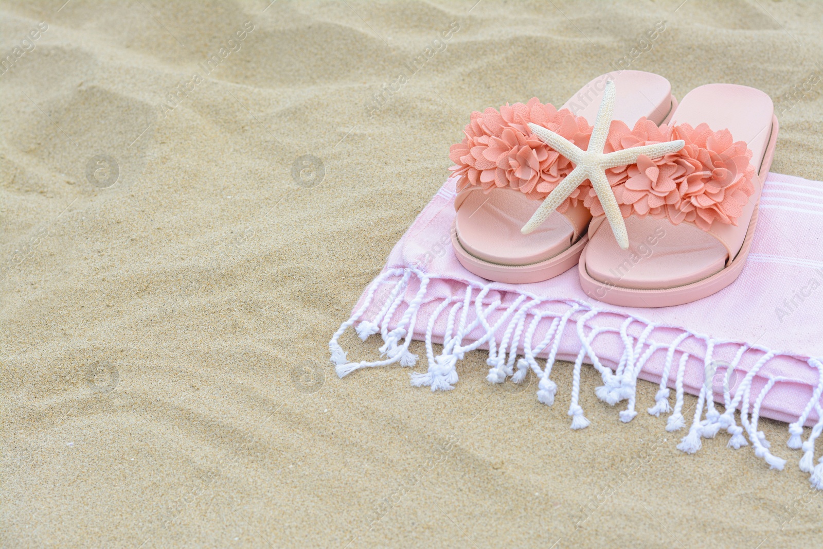 Photo of Blanket with stylish slippers and starfish on sand outdoors, space for text. Beach accessories