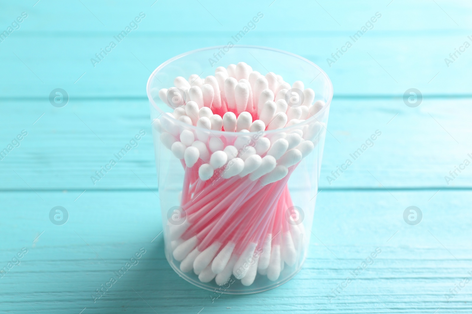 Photo of Plastic container with cotton swabs on wooden background