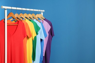 Photo of Bright clothes on blue background, space for text. Rainbow colors
