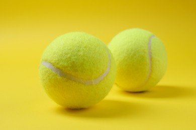 Photo of Two bright tennis balls on yellow background