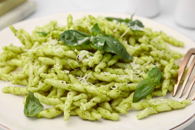 Plate of delicious trofie pasta with pesto sauce, cheese and basil leaves on table, closeup