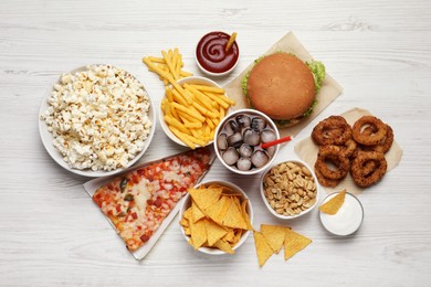 Photo of French fries, pizza and other fast food on white wooden table, flat lay