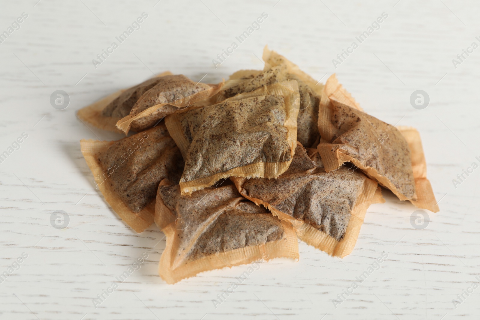 Photo of Heap of used tea bags on white wooden table