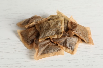 Photo of Heap of used tea bags on white wooden table