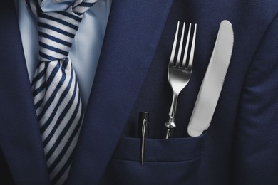 Photo of Cutlery and pen in breast pocket of men`s jacket as background, closeup. Business lunch concept
