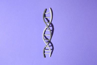 Photo of Plasticine model of DNA molecular chain on violet background, top view