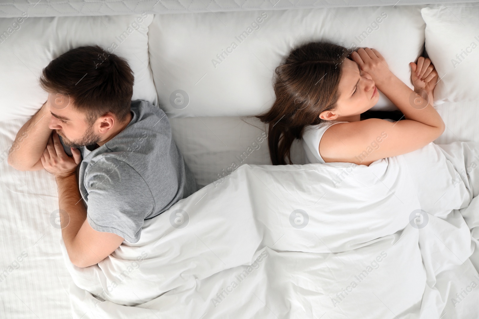 Photo of Unhappy couple with relationship problems after quarrel in bed, above view