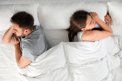 Unhappy couple with relationship problems after quarrel in bed, above view