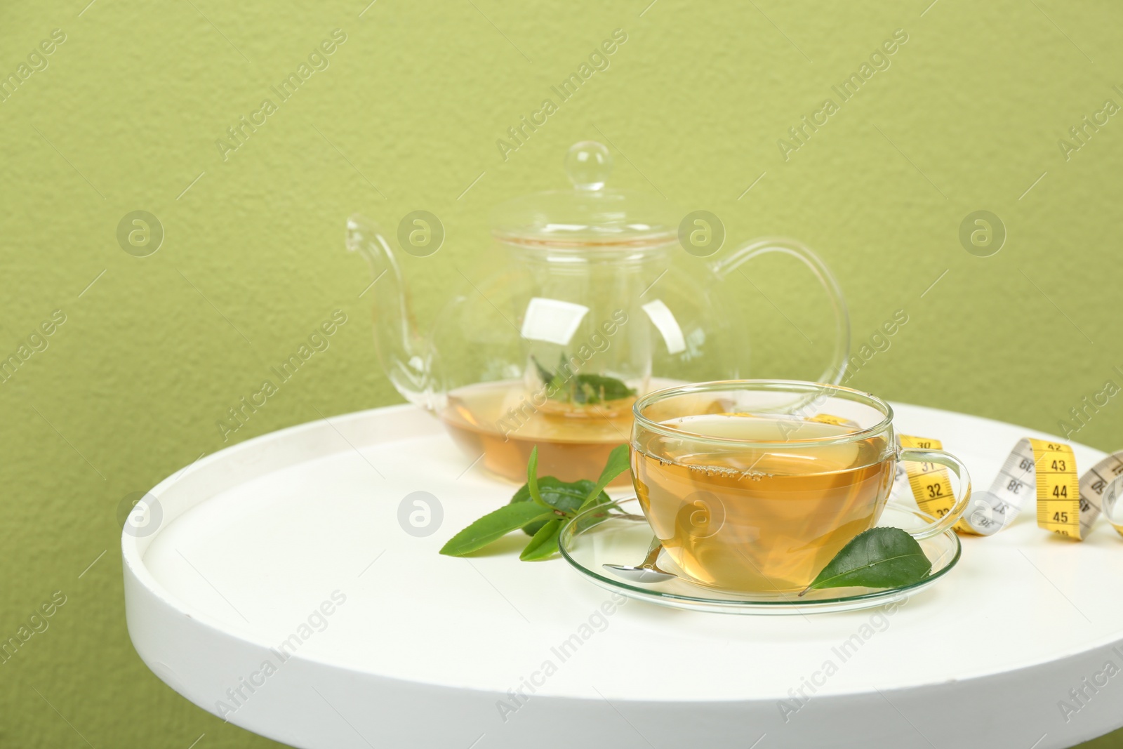 Photo of Herbal diet tea and measuring tape on white table