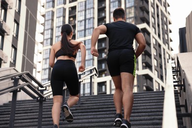 Healthy lifestyle. Couple running up steps outdoors, low angle view