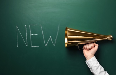 Photo of Man holding megaphone and word NEW on chalkboard