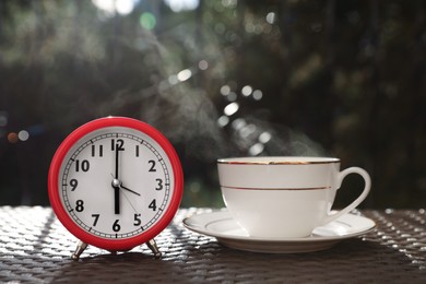Photo of Alarm clock and cup with hot drink on table