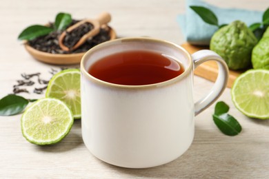 Photo of Cup of tasty bergamot tea on white wooden table