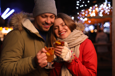 Happy couple with mulled wine at winter fair