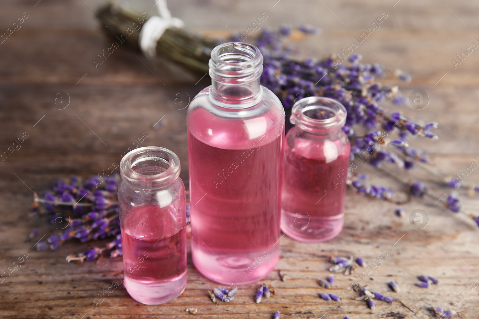 Photo of Bottles with aromatic lavender oil on wooden table