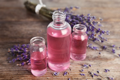 Photo of Bottles with aromatic lavender oil on wooden table