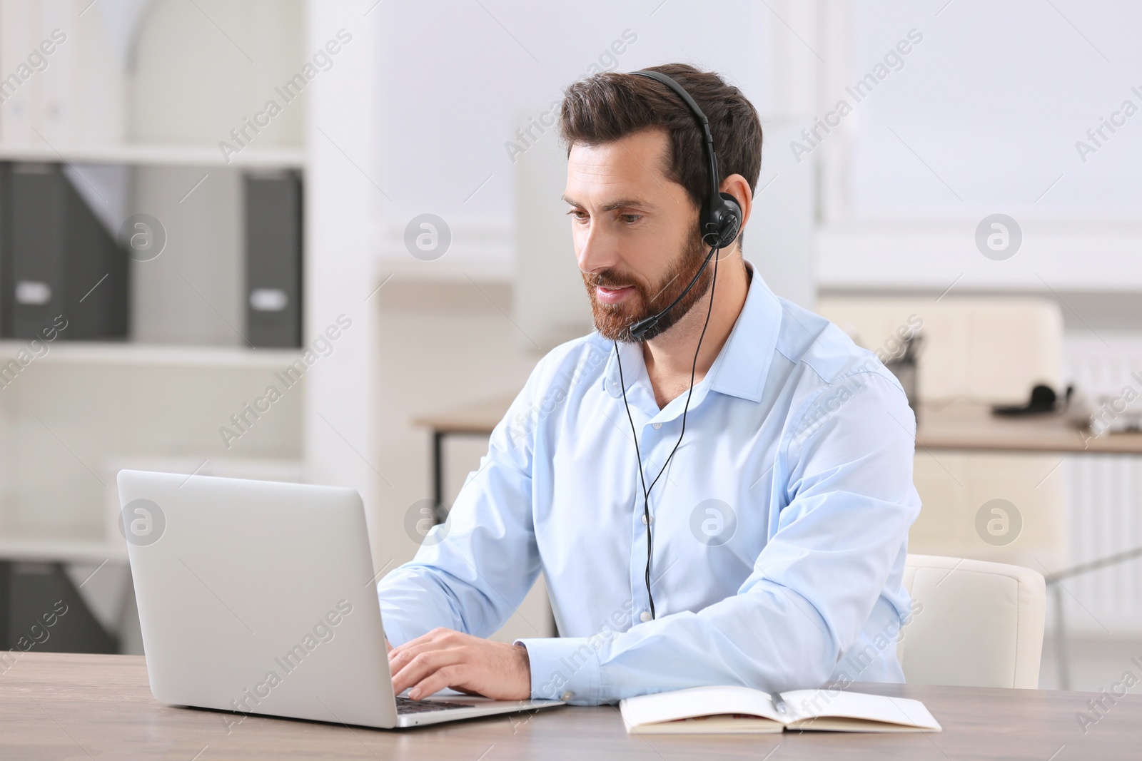 Photo of Hotline operator with headset working in office