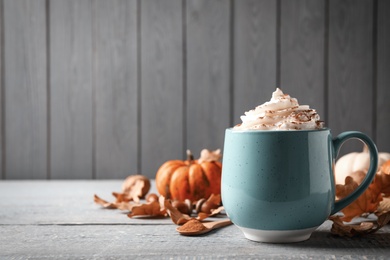 Photo of Delicious pumpkin latte on grey wooden table. Space for text
