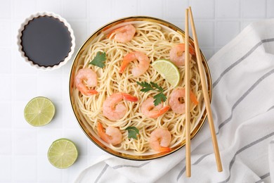 Tasty spaghetti with shrimps, lime, parsley and soy sauce on white tiled table, flat lay