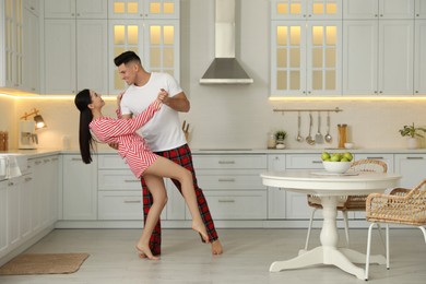 Happy couple wearing pyjamas and dancing in kitchen