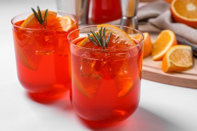 Photo of Aperol spritz cocktail, rosemary and orange slices on white wooden table, closeup