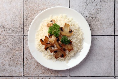 Photo of Delicious rice with parsley and mushrooms on tiled table, top view