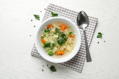 Photo of Bowl of fresh homemade vegetable soup served on white wooden table, flat lay