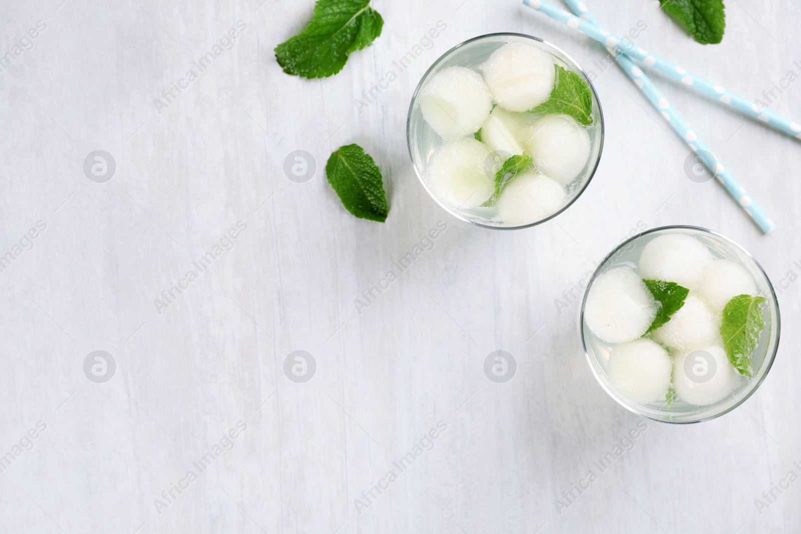 Photo of Glasses with melon ball drinks on light table, flat lay composition with space for text