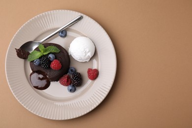 Photo of Delicious chocolate fondant served with fresh berries and ice cream on beige background, top view. Space for text