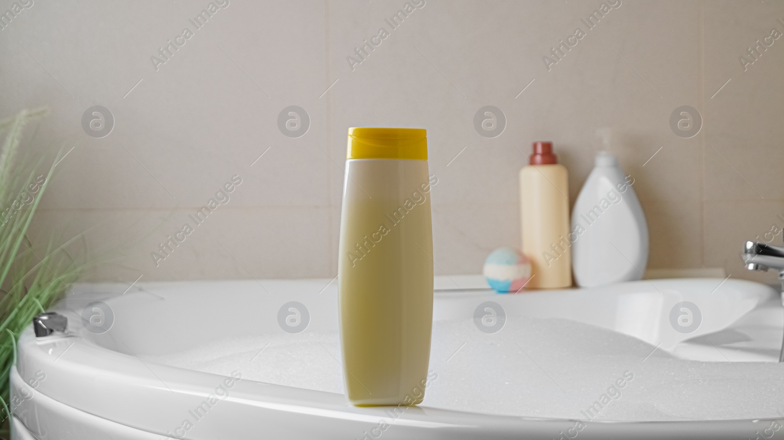 Photo of Beige bottle of bubble bath on tub indoors