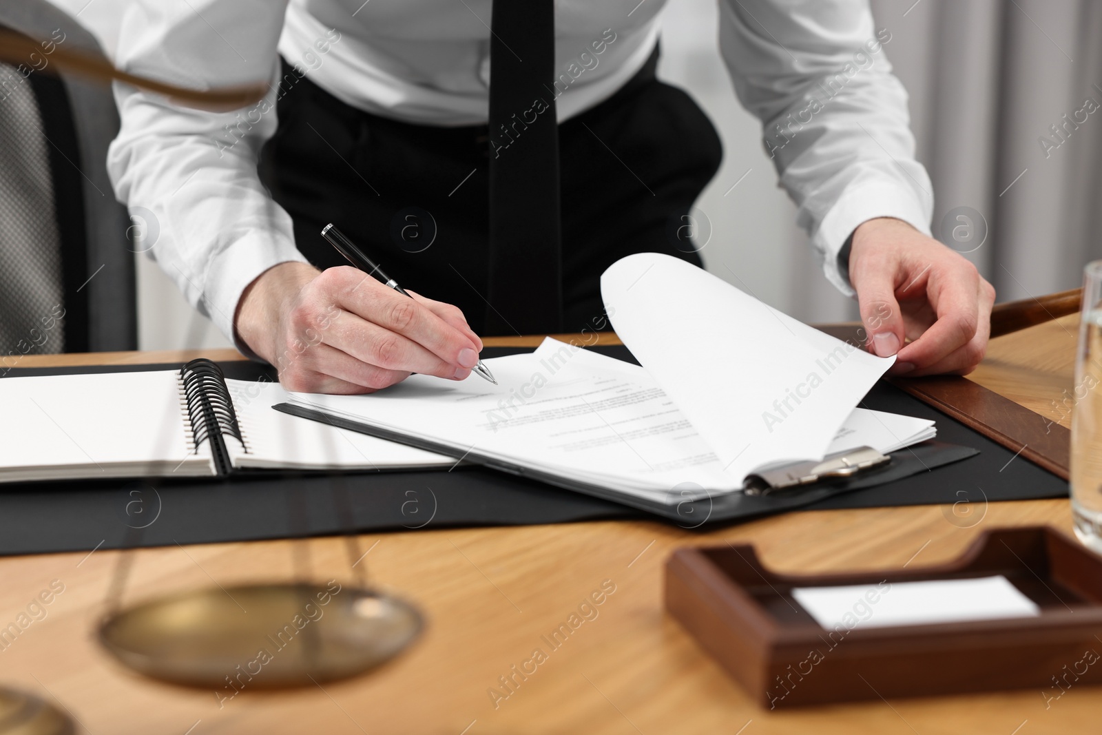 Photo of Lawyer working with documents at wooden table indoors, closeup