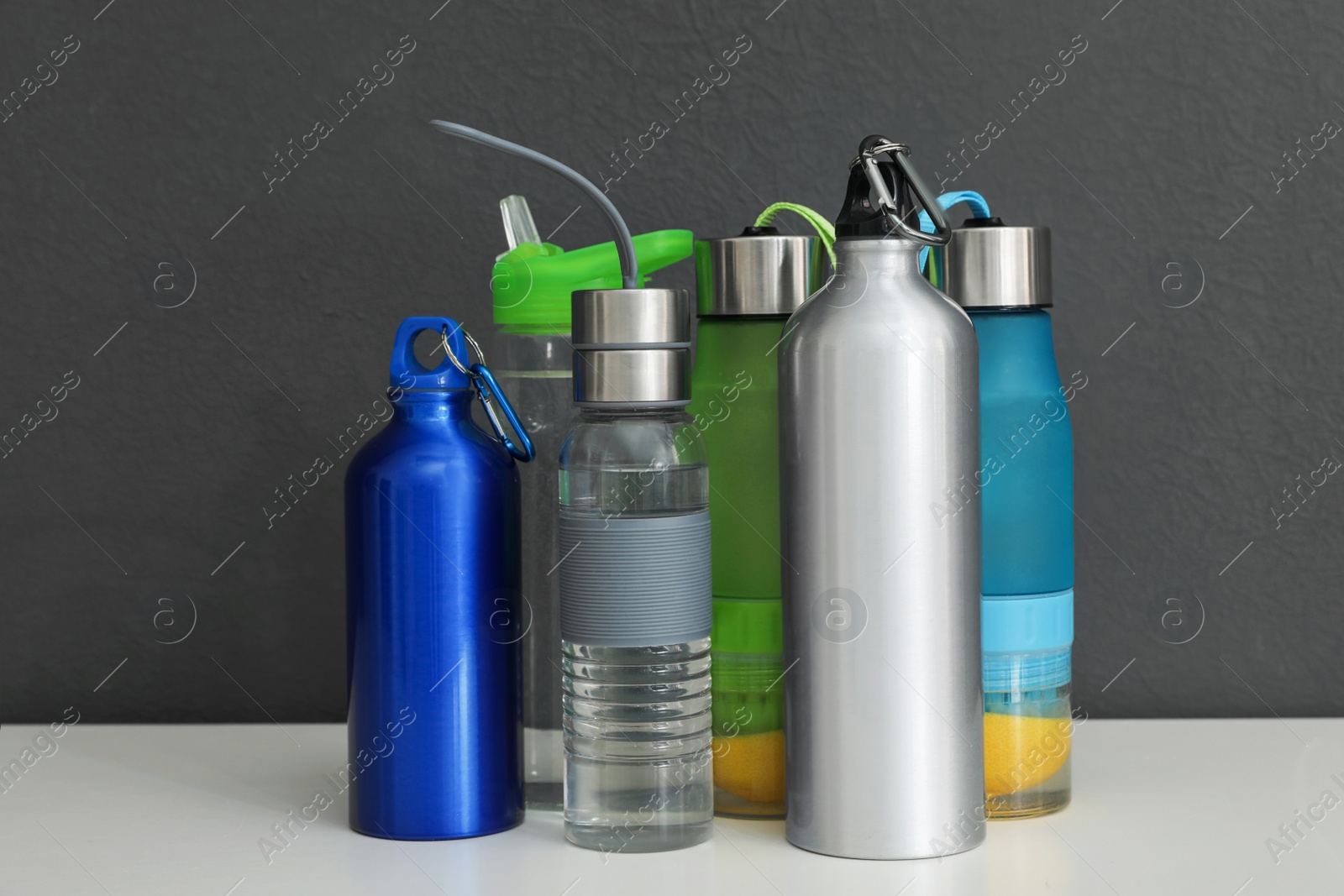 Photo of Different water bottles for sports on gray background