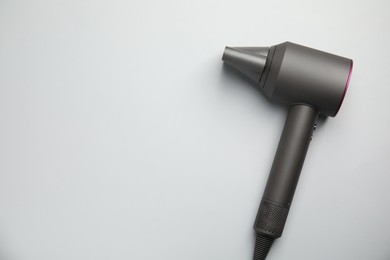 Modern hair dryer on light grey background, top view. Space for text