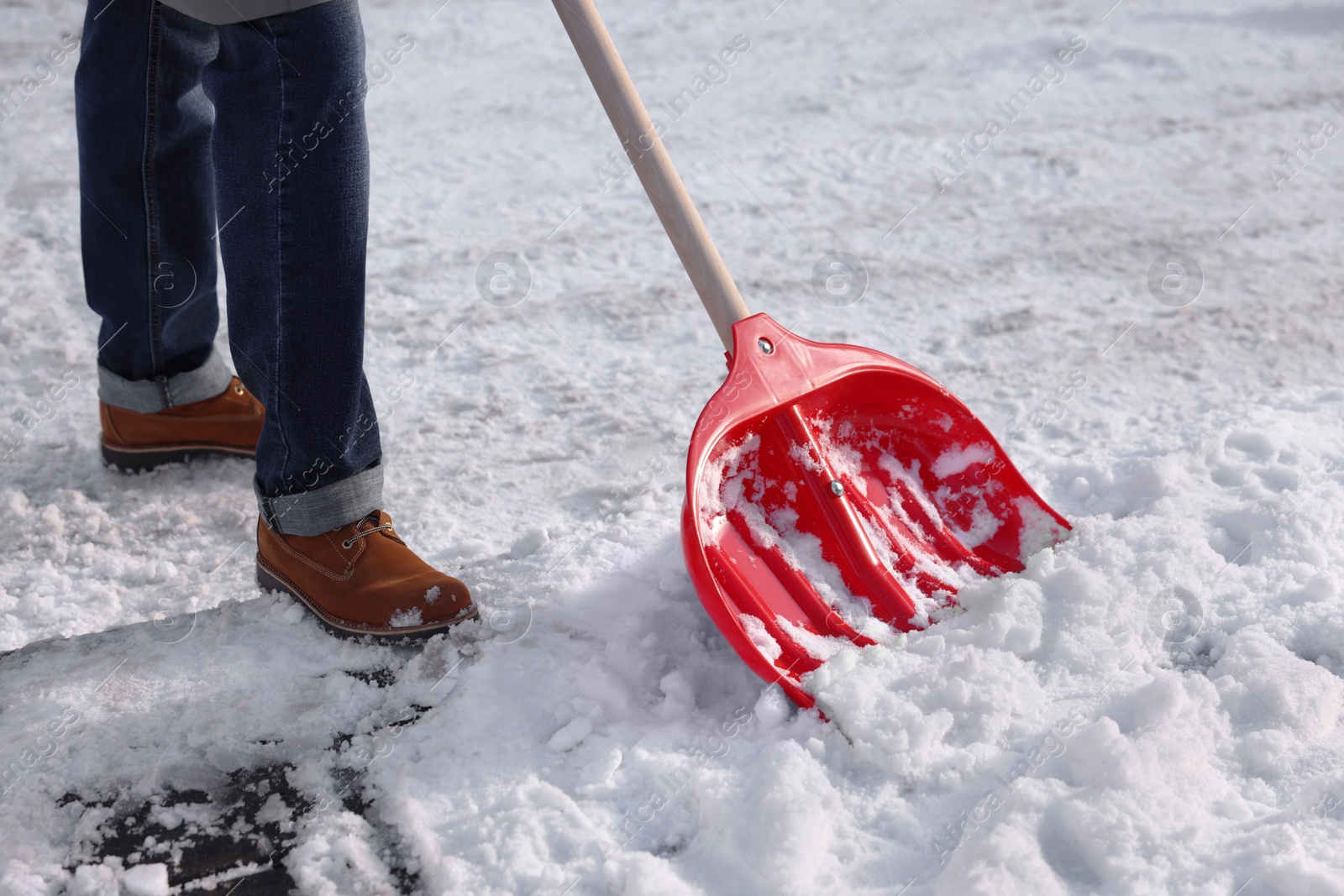 Photo of Man shoveling snow outdoors on sunny day, closeup