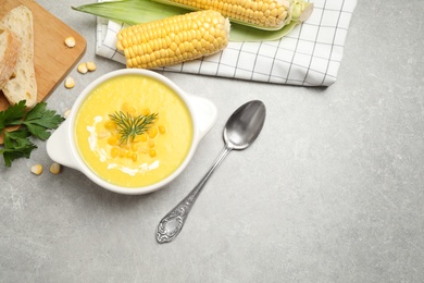 Delicious creamy corn soup served on grey table, flat lay. Space for text