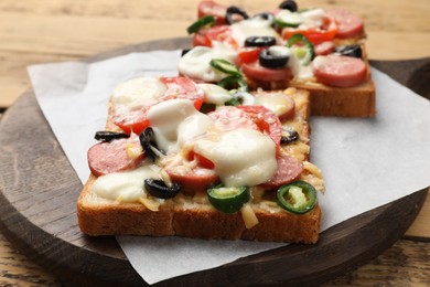 Photo of Tasty pizza toasts on wooden table, closeup