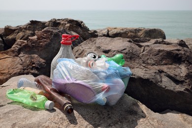 Photo of Garbage on stones near sea. Environmental Pollution concept