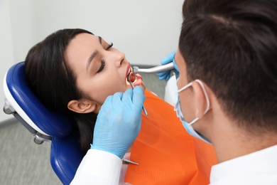 Photo of Professional dentist working with patient in clinic