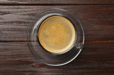 Photo of Cup of aromatic coffee on wooden table, top view