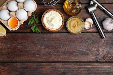 Photo of Tasty tartar sauce and ingredients on wooden table, flat lay. Space for text