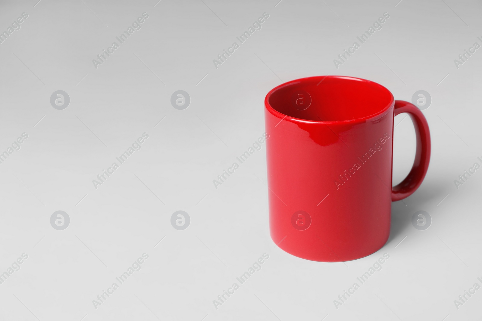 Red ceramic mug on light grey background. Space for text Photo of Red ceramic mug on light grey background. Space for text