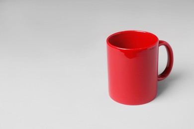 Photo of Red ceramic mug on light grey background. Space for text