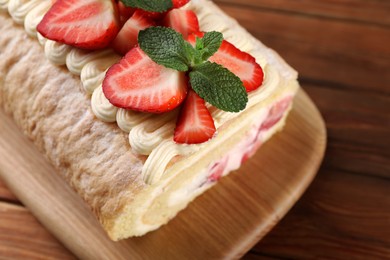 Delicious cake roll with strawberries and cream on table closeup