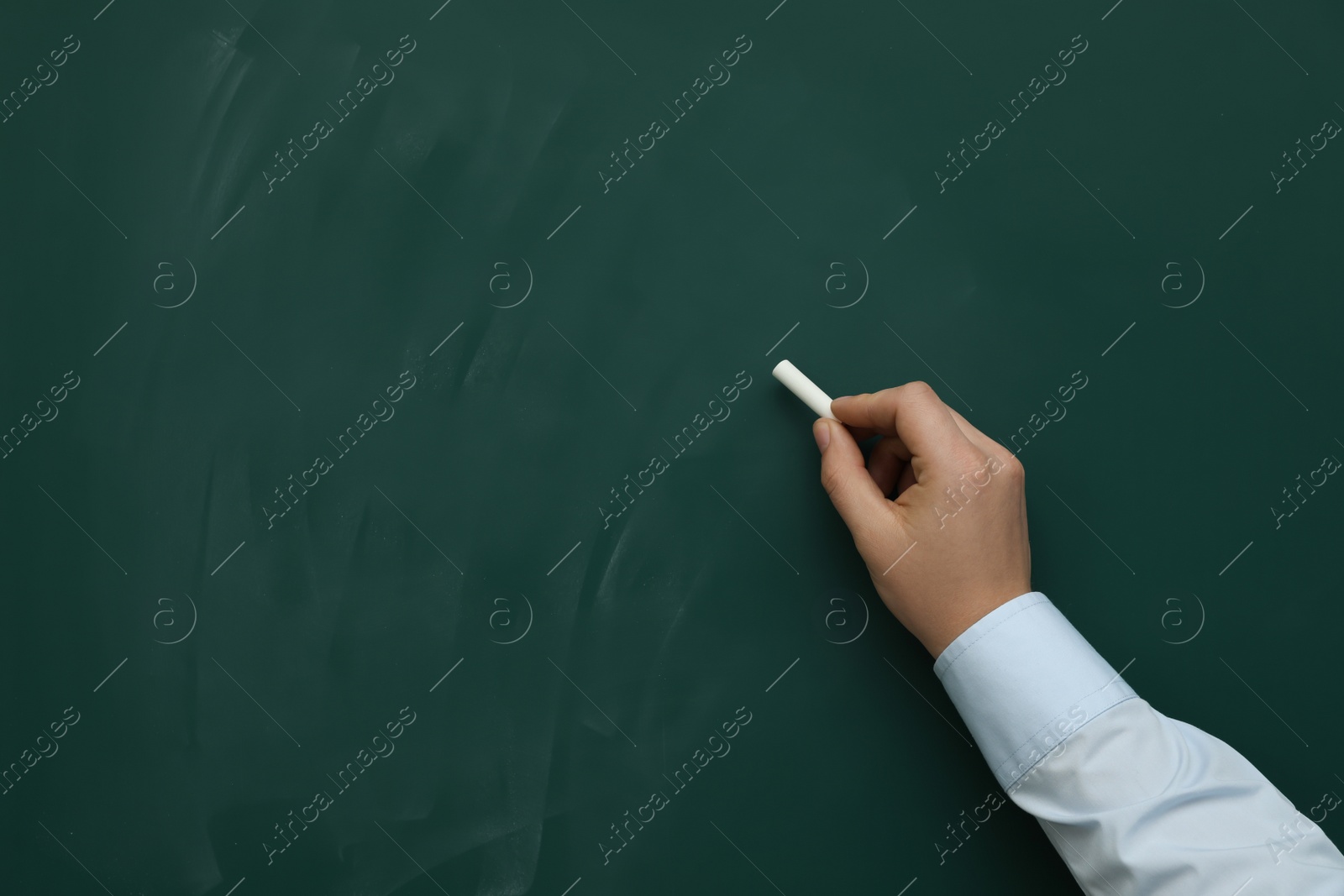 Photo of Man with white chalk near green board, closeup. Space for text
