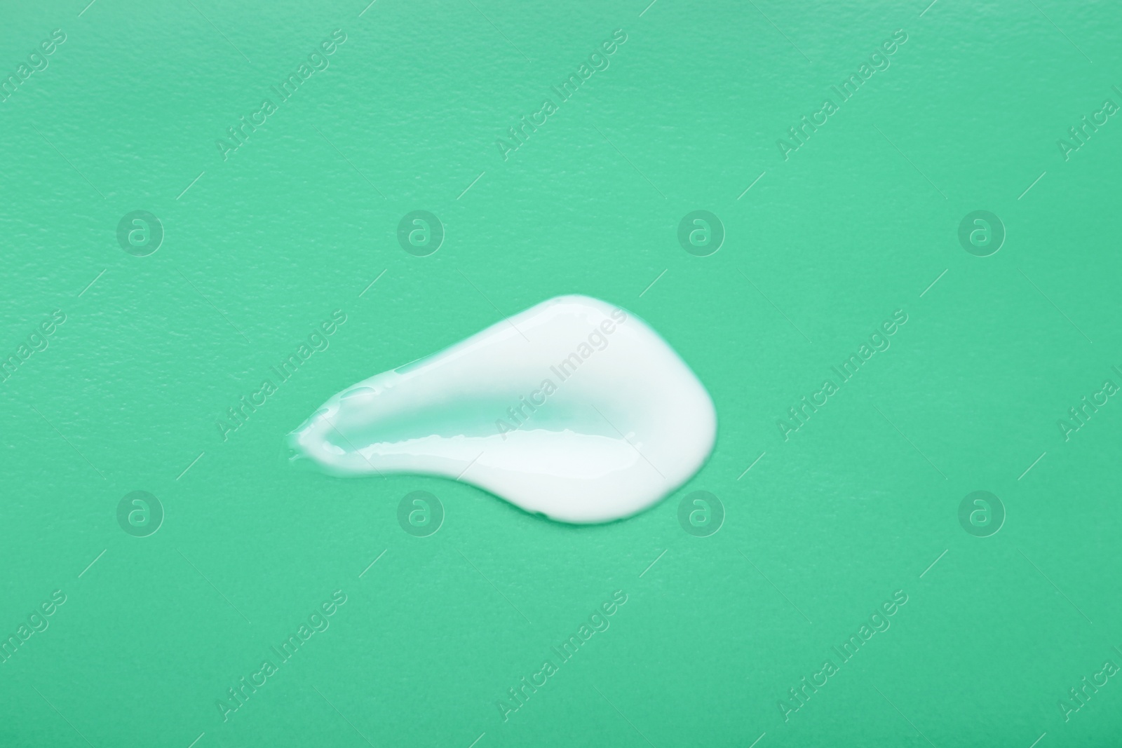 Photo of Body cream sample on light green background, top view. Cosmetic product