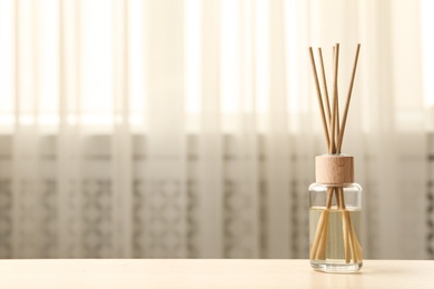 Photo of Reed air freshener on table indoors, space for text
