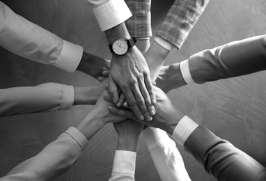 Image of People holding hands together over stone background, top view. Unity concept